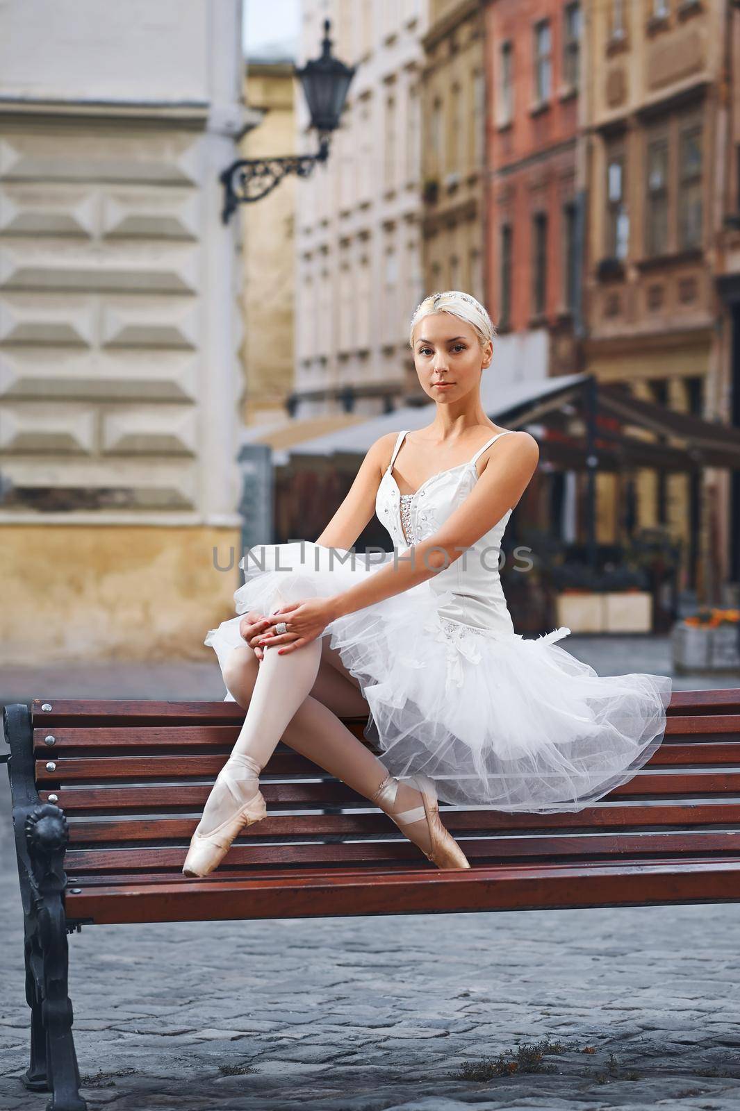 Portrait of a beautiful female ballet dancer resting on the bench in the city center sitting gracefully beauty elegance urban fashion concept.