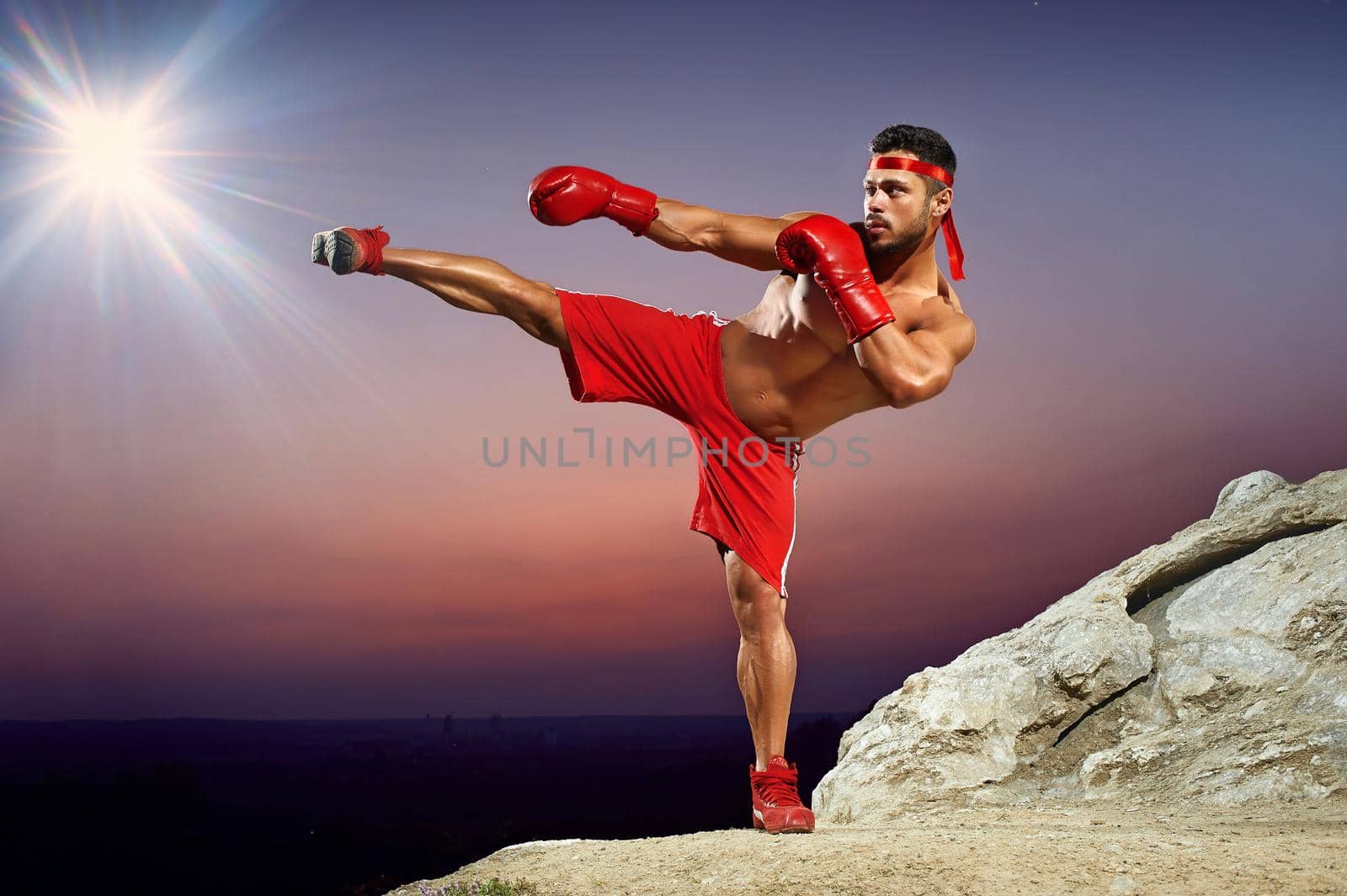Boxer in training on the hillside at sunset, evening workouts, side kick, red boxing gloves, red boxing form,man with a naked torso, muscles, developed muscles, muscular body, athlete. by SerhiiBobyk