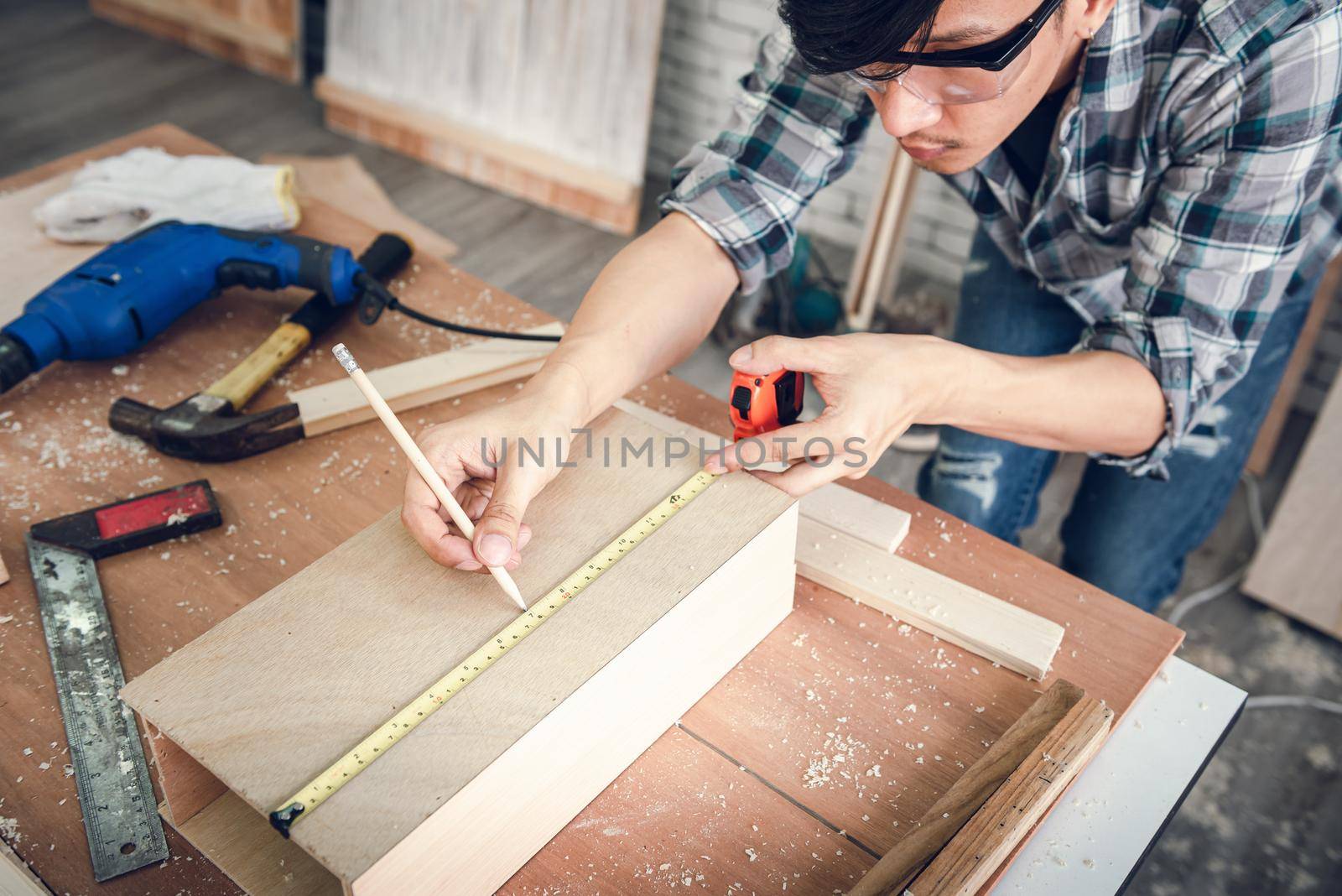 Carpenter Man is Working Timber Woodworking in Carpentry Workshops, Craftsman is Using Tape Measure to Measuring Timber Frame for Wooden Furniture in Workshop. DIY Workmanship, Job Occupation Concept.