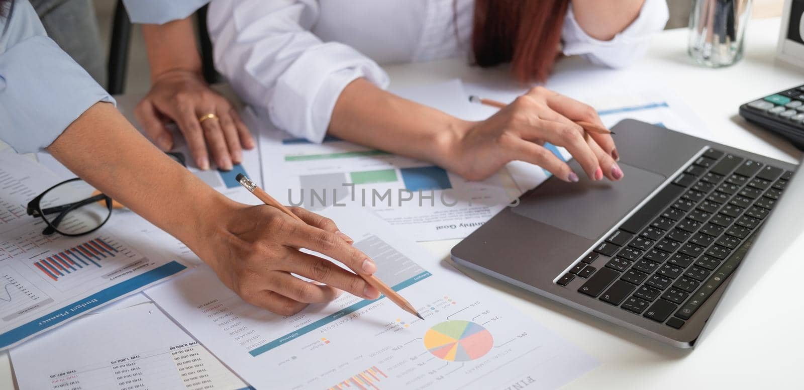 Close up business team using a calculator and laptop computer to calculate the numbers on his desk in a office by nateemee