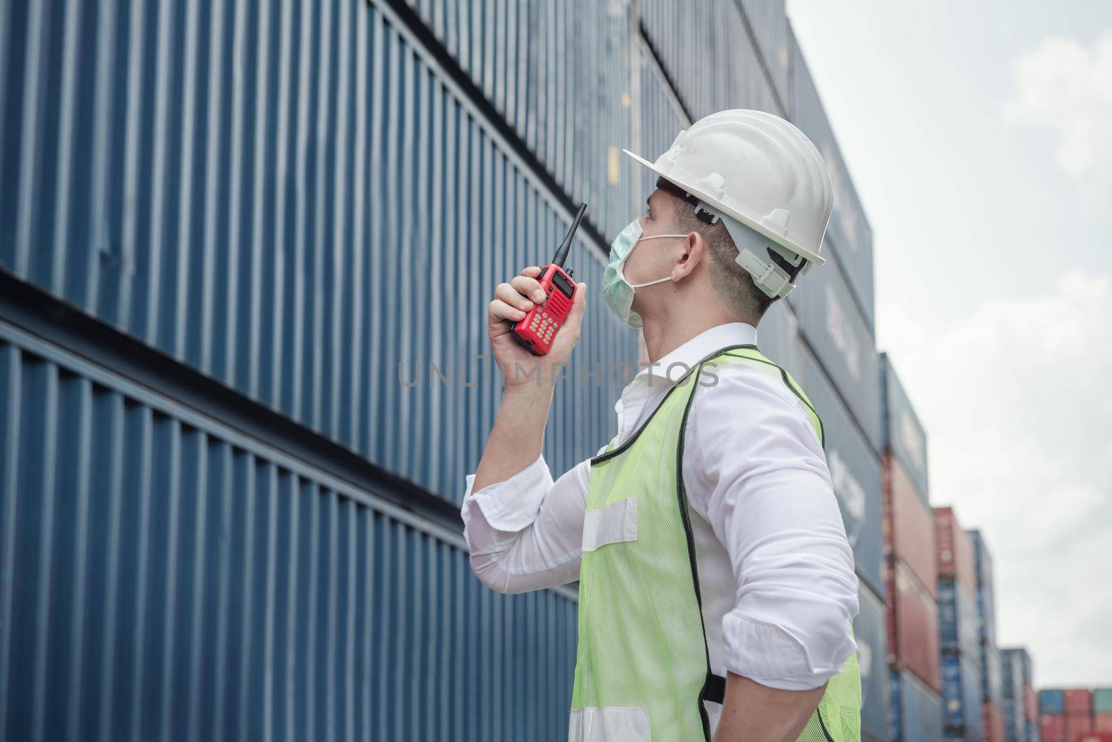 Transport Engineer Man Wearing Medical Face Mask for Prevention Coronavirus Epidemic Situation in Containers Logistic Shipping Yard. Transportation and Logistics after Coronavirus Covid-19 New Normal