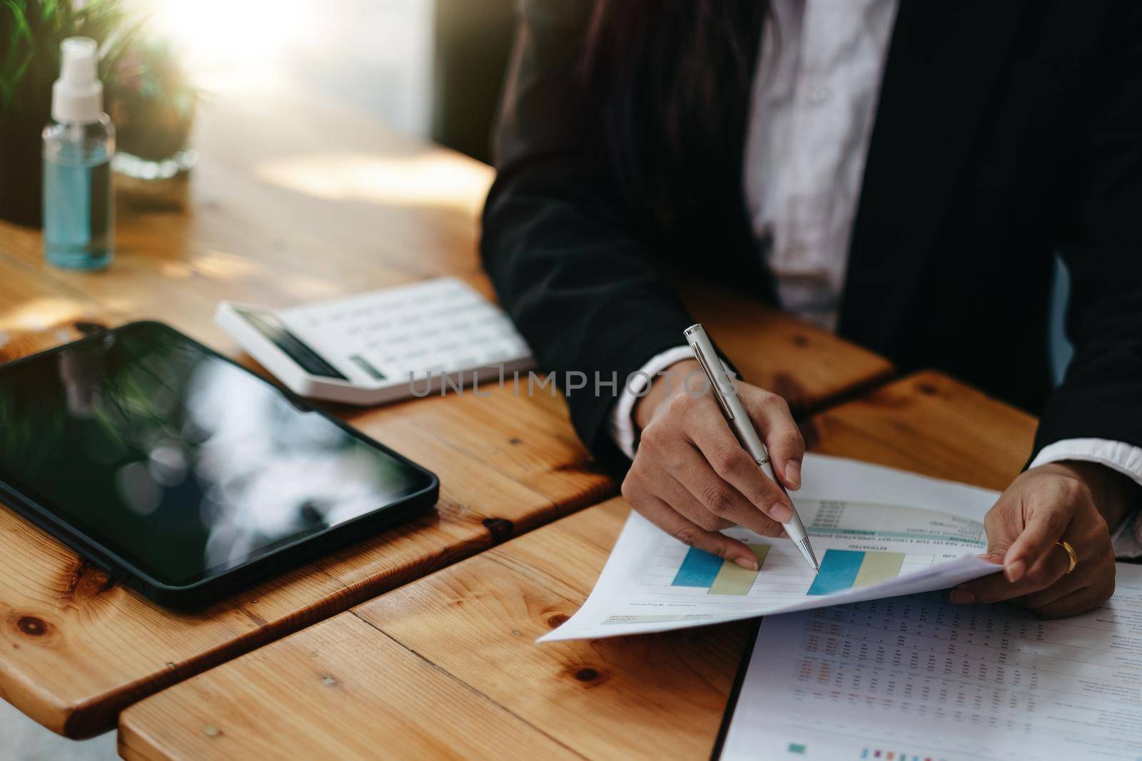 Close up businesswoman working on desk office using a calculator to calculate the numbers on chart report, finance accounting concept