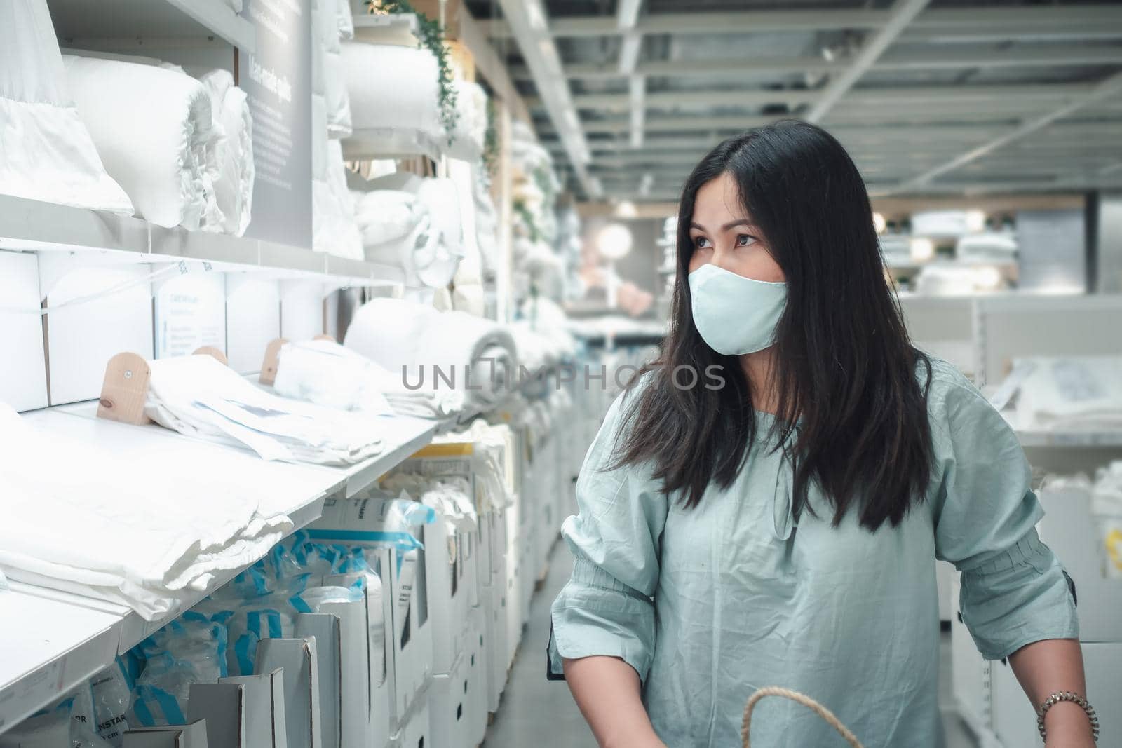 Customer Asian Woman Wearing Face Mask With Shopping Cart in Supermarket Department Store Shop While Choosing and Looking Goods on Shelf During Covid-19 Pandemic. Coronavirus Covid Situation 