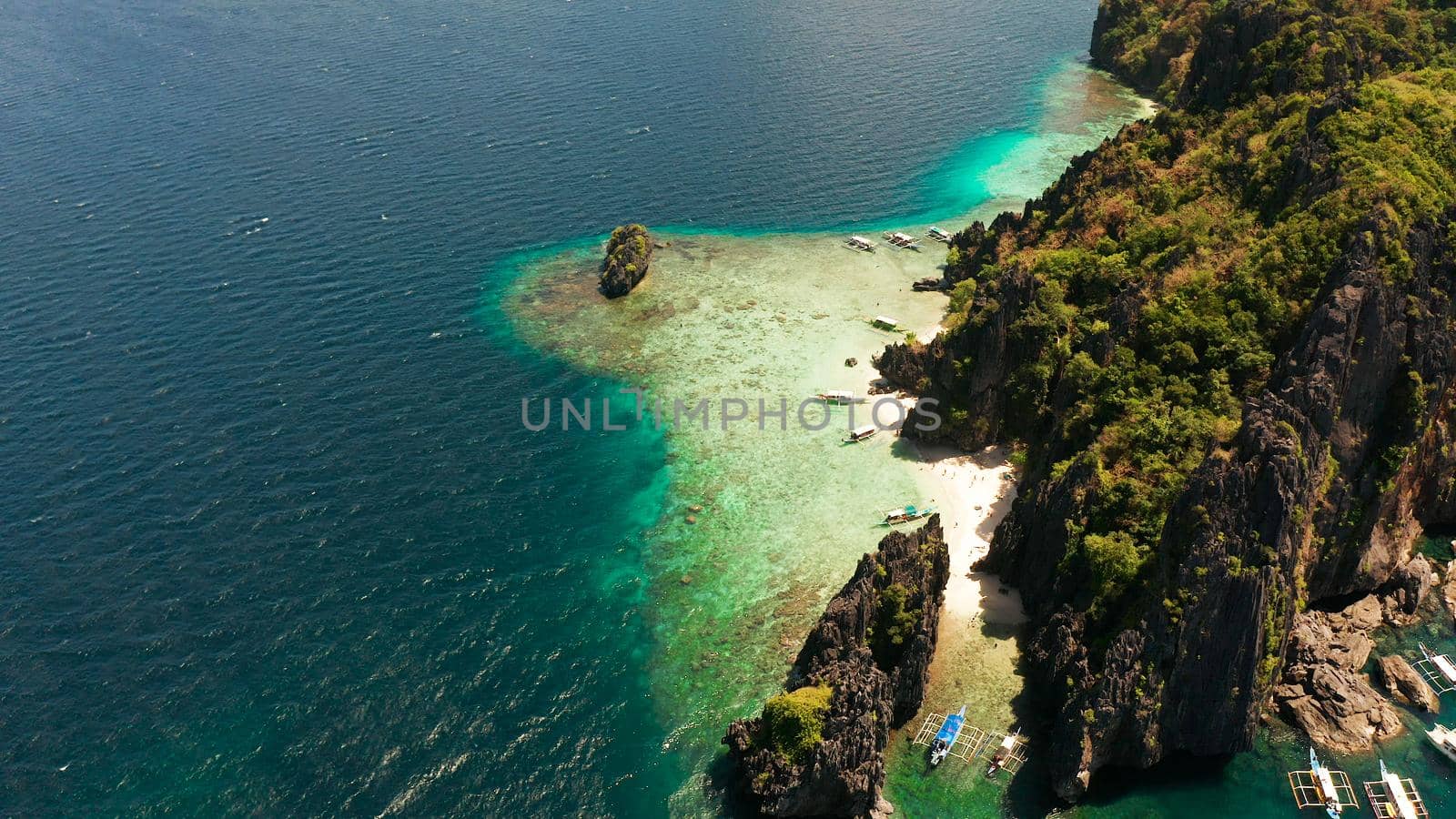 Aerial drone tropical landscape bay with beach and clear blue water surrounded by cliffs. El nido, Philippines, Palawan. Seascape with tropical rocky islands, ocean blue water. Summer and travel vacation concept