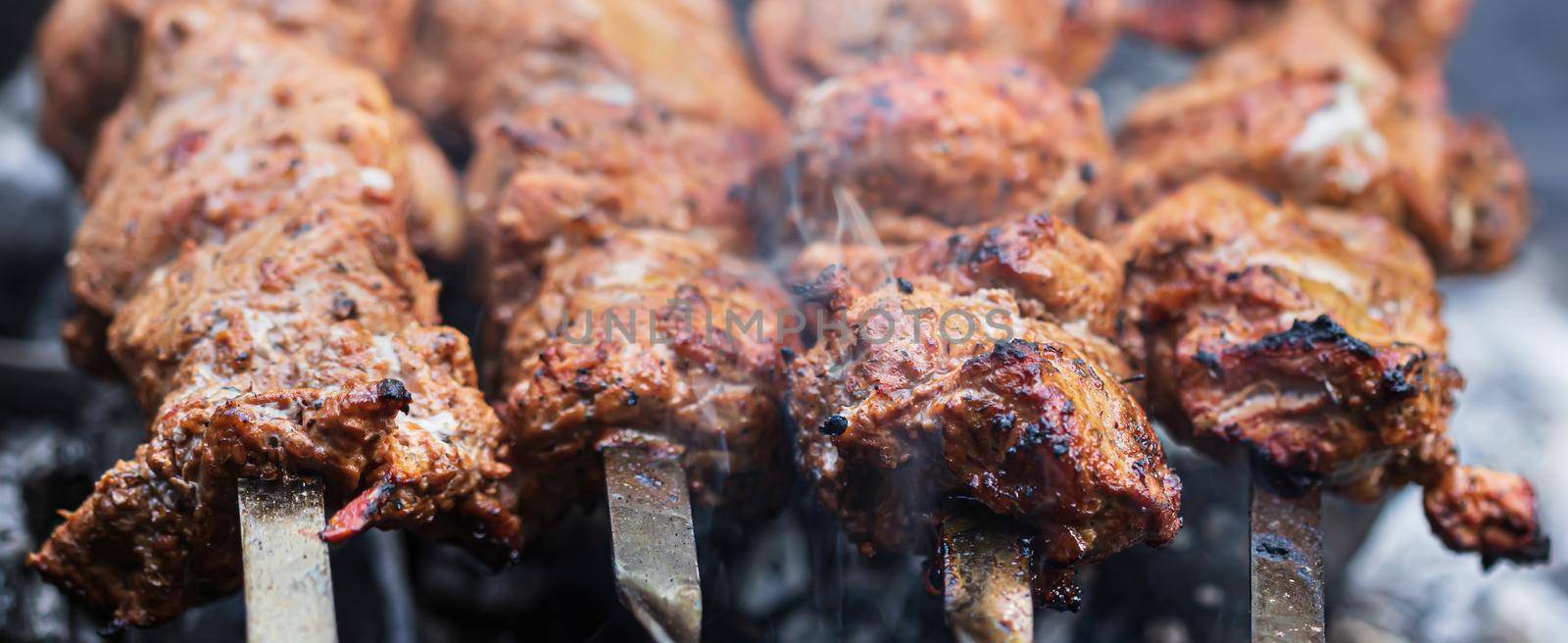Meat on skewers. Marinated shashlik preparing on a barbecue grill over charcoal. Appetizing meat grilled on skewers. Cooking shashlik. Grilling pork on coal
