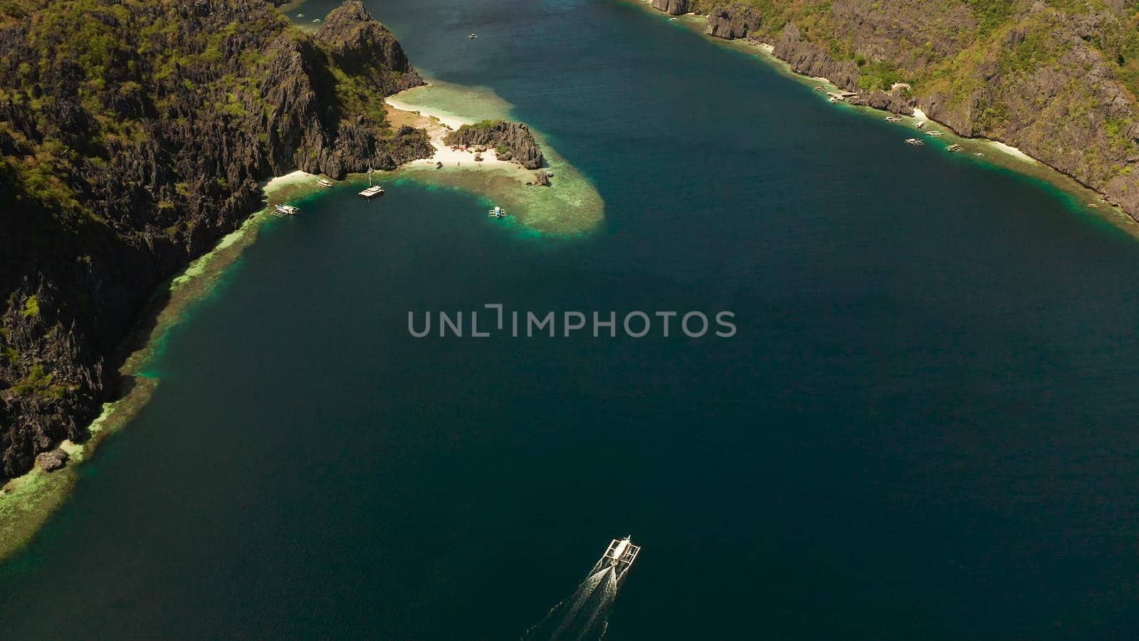 Tropical landscape bay with beach and clear blue water surrounded by cliffs, aerial drone. El nido, Philippines, Palawan. Seascape with tropical rocky islands, ocean blue water. Summer and travel vacation concept
