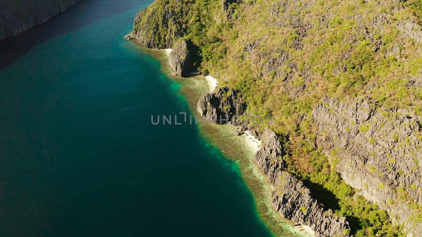 Tropical landscape bay with beach and clear blue water surrounded by cliffs, aerial drone. El nido, Philippines, Palawan. Seascape with tropical rocky islands, ocean blue water. Summer and travel vacation concept