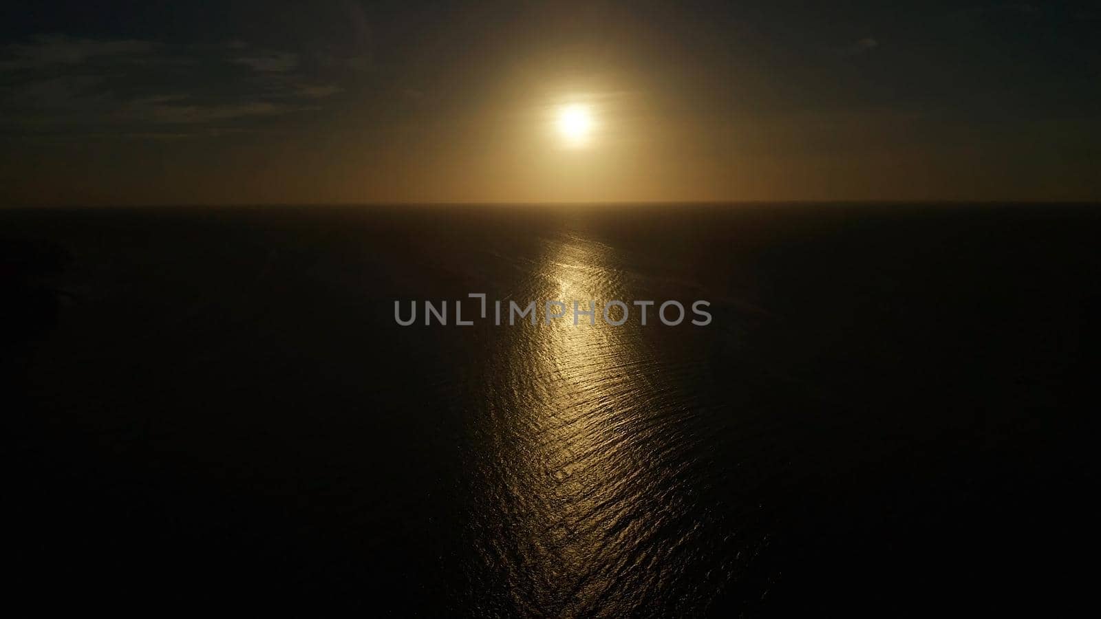 Sunset above the sea surface with waves, aerial drone. Reflected sun on a water surface. Sunset over ocean. Seascape, Summer and travel vacation concept
