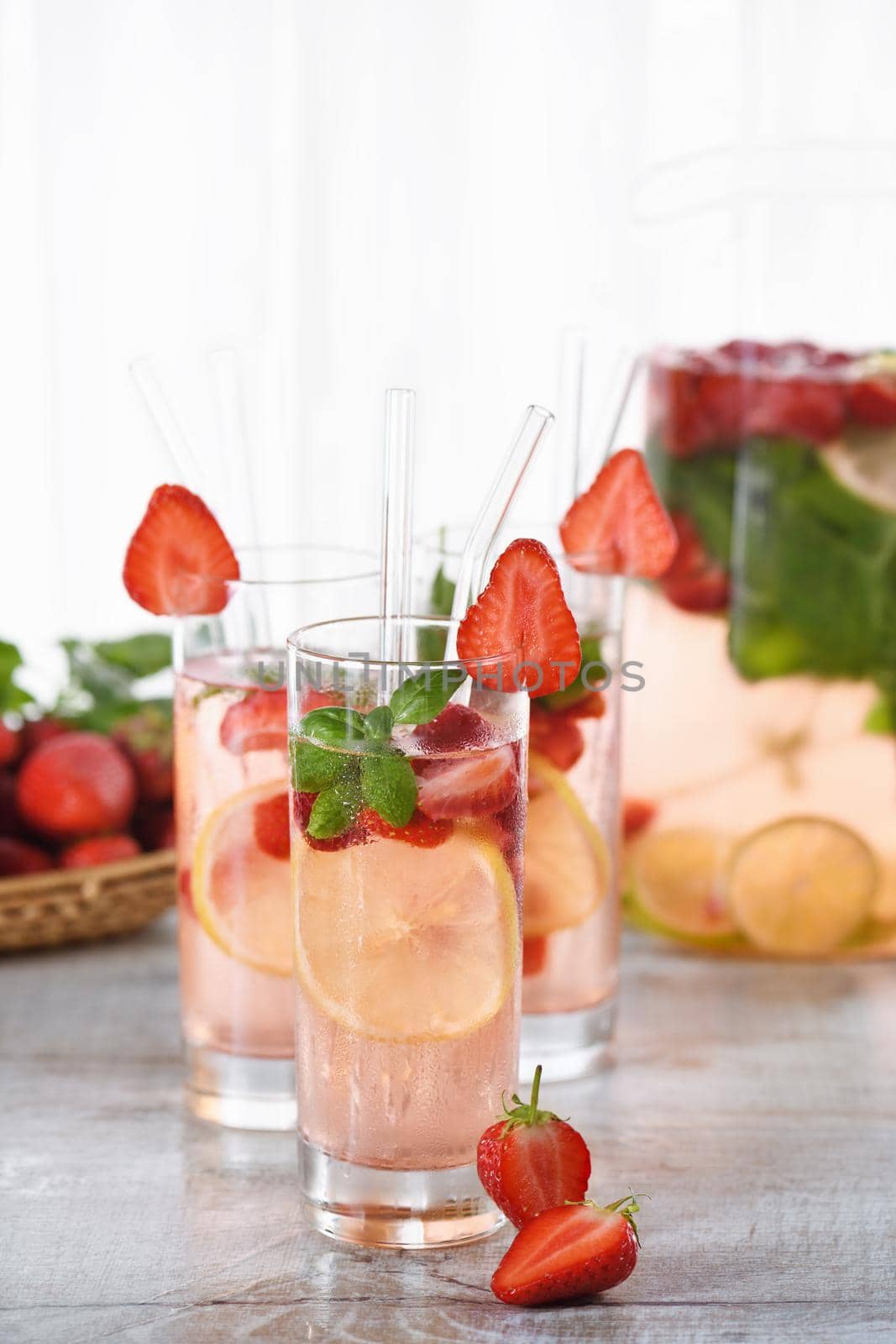 Summer strawberry cocktail or lemonade with basil. Cold refreshing organic soft drink with ripe berries in a glass