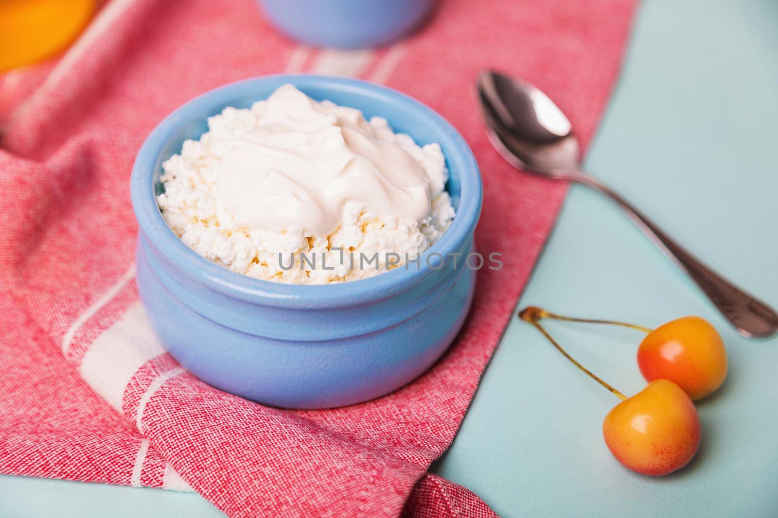 Cottage cheese in a blue bowl with sour cream and honey. Morning breakfast.