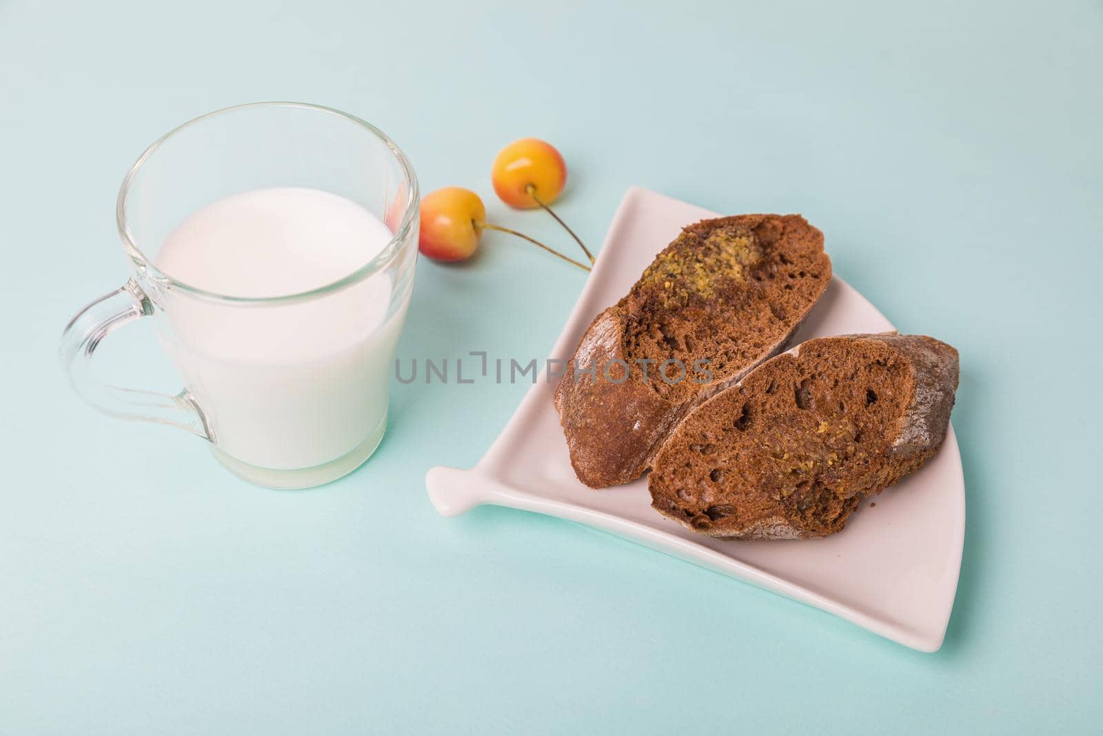 Pieces of rye bread on a white plate, next to a mug with milk on a blue background. Morning breakfast