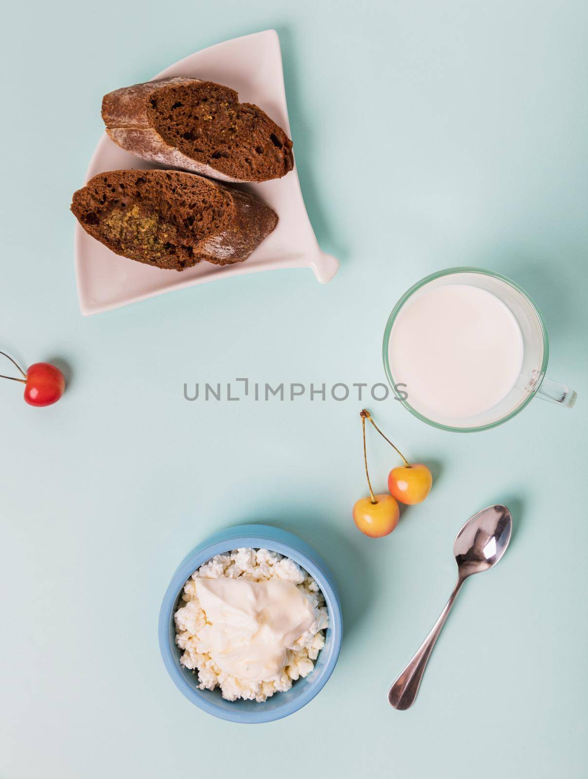 Cottage cheese in a blue bowl with sour cream and honey. Toasted bread in a plate. Morning breakfast.