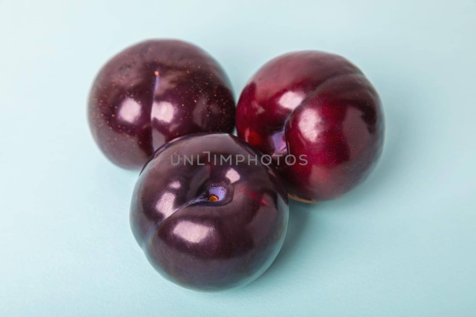 Three large plums on a blue background. Delicious berry for dessert.