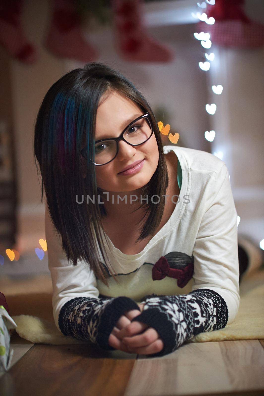 2018, Relaxing on holidays. Vertical portrait of a cute young girl smiling to the camera lying near the Christmas tree soft focus and noise,2019