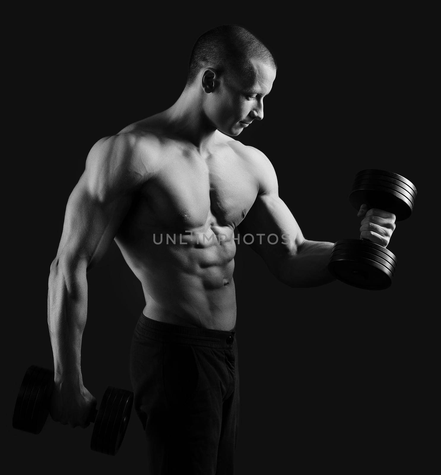 Perfecting his shape. Studio monochrome portrait of a shirtless hot and sexy masculine male bodybuilder pumping iron