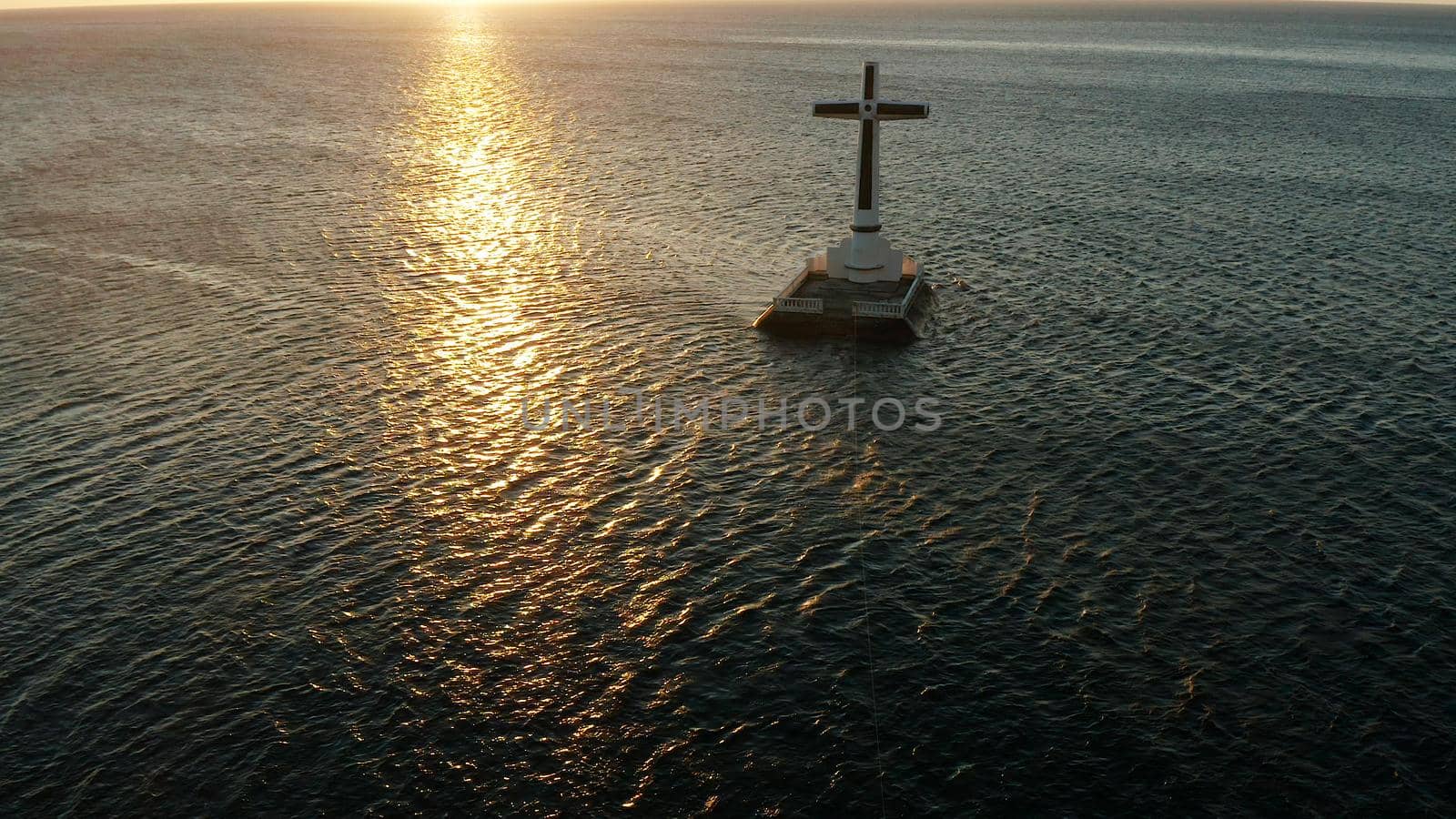 Catholic cross in sunken cemetery in the sea at sunset, aerial view. Sunset at Sunken Cemetery Camiguin Island Philippines.