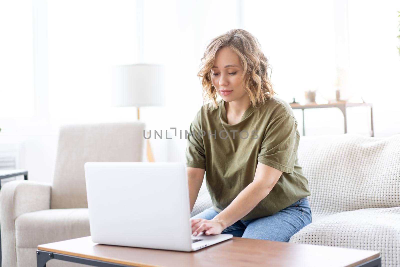 Woman use laptop computer while sitting couch big window background home interior Freelance female working from home Distance learning student relaxing watch lessons video conference .