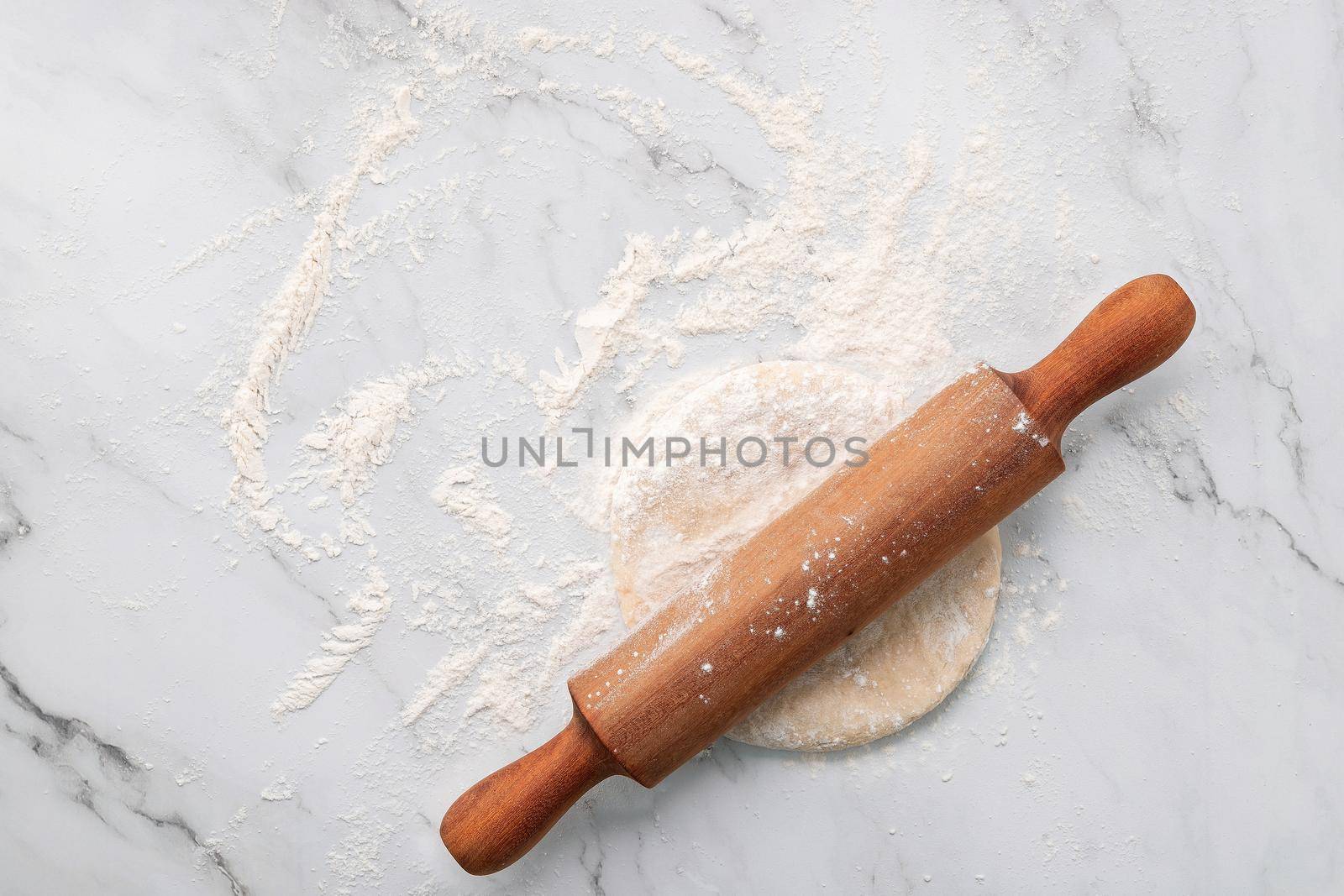 Scattered wheat flour and fresh homemade yeast dough kneaded on marble table with rolling pin on marble table flat lay. by kerdkanno