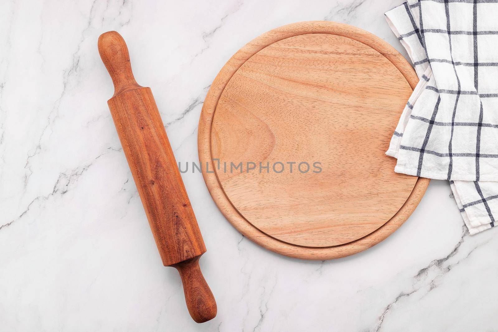 Empty wooden pizza platter with napkin and rolling pin set up on marble stone kitchen table. Pizza board and tablecloth on white marble background. by kerdkanno