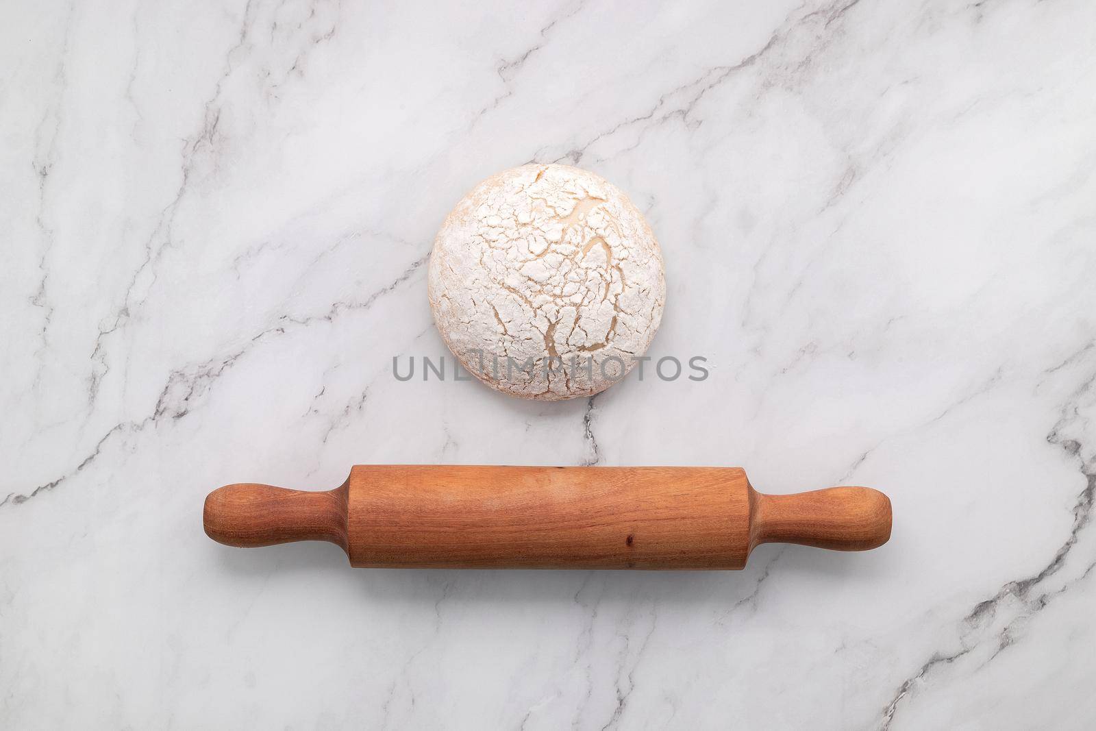 Fresh homemade yeast dough resting on marble table flat lay with rolling pin.