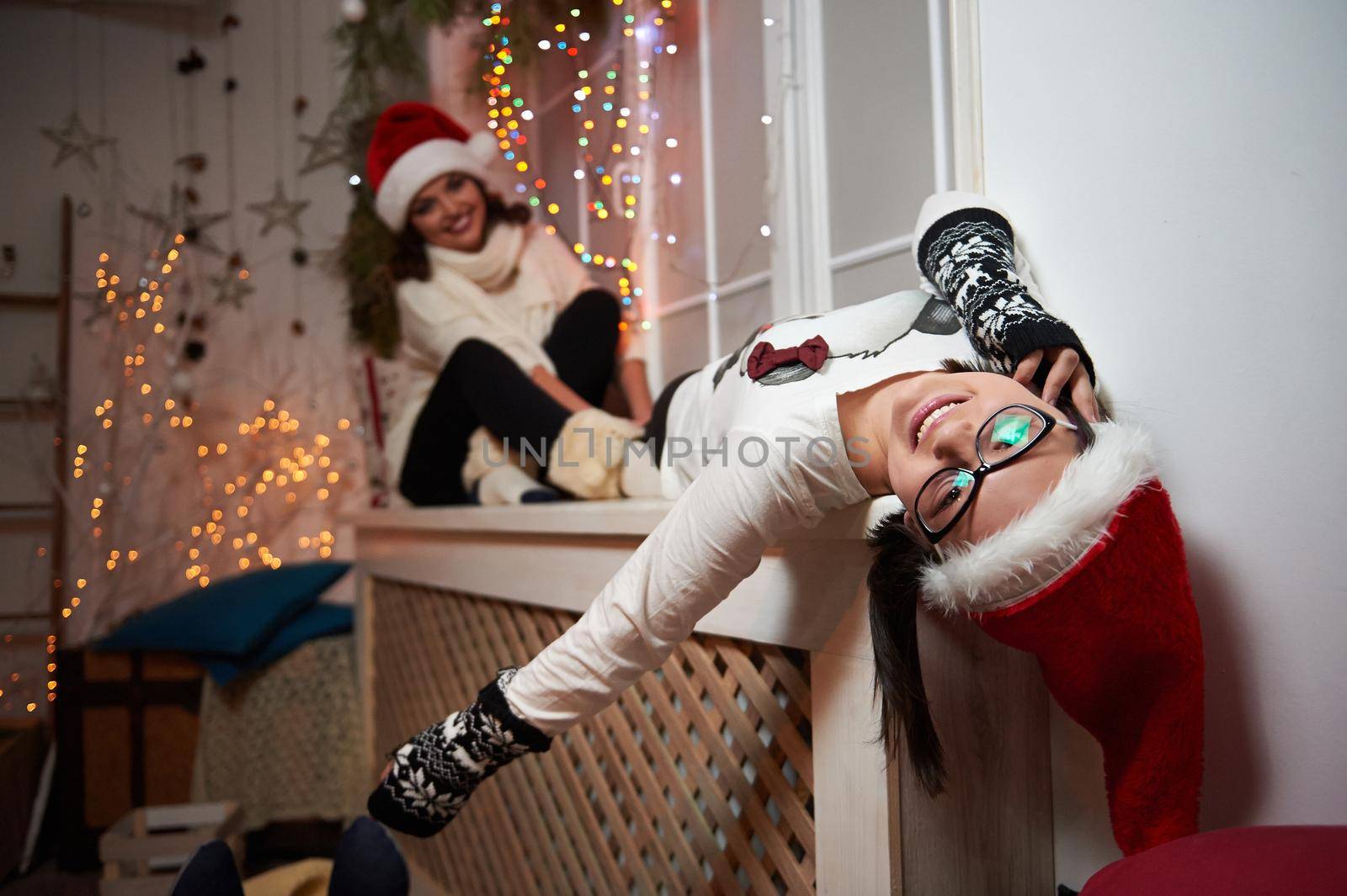 Having fun with mom. Young girl having fun with her mother at home on Christmas eve posing together on a window sill soft focus and noise