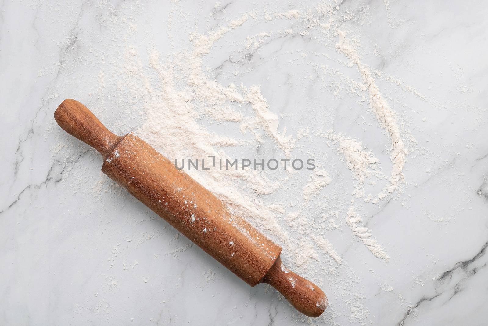 Scattered wheat flour and rolling pin set up on white marble background flat lay. by kerdkanno