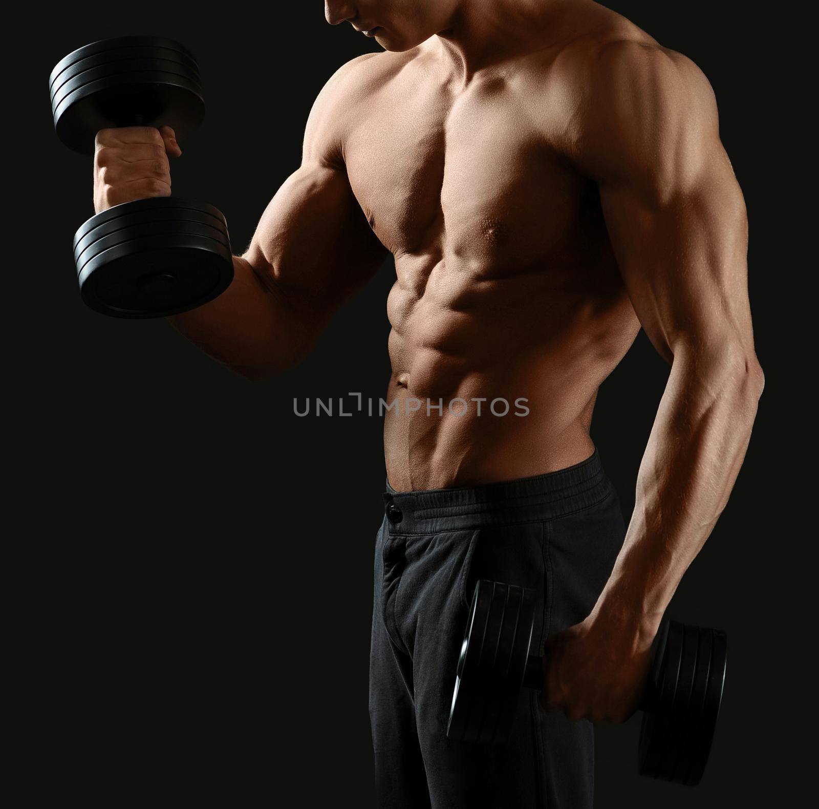 Muscles burning. Cropped shot of a shirtless bodybuilder working out with dumbbells showing off his toned torso