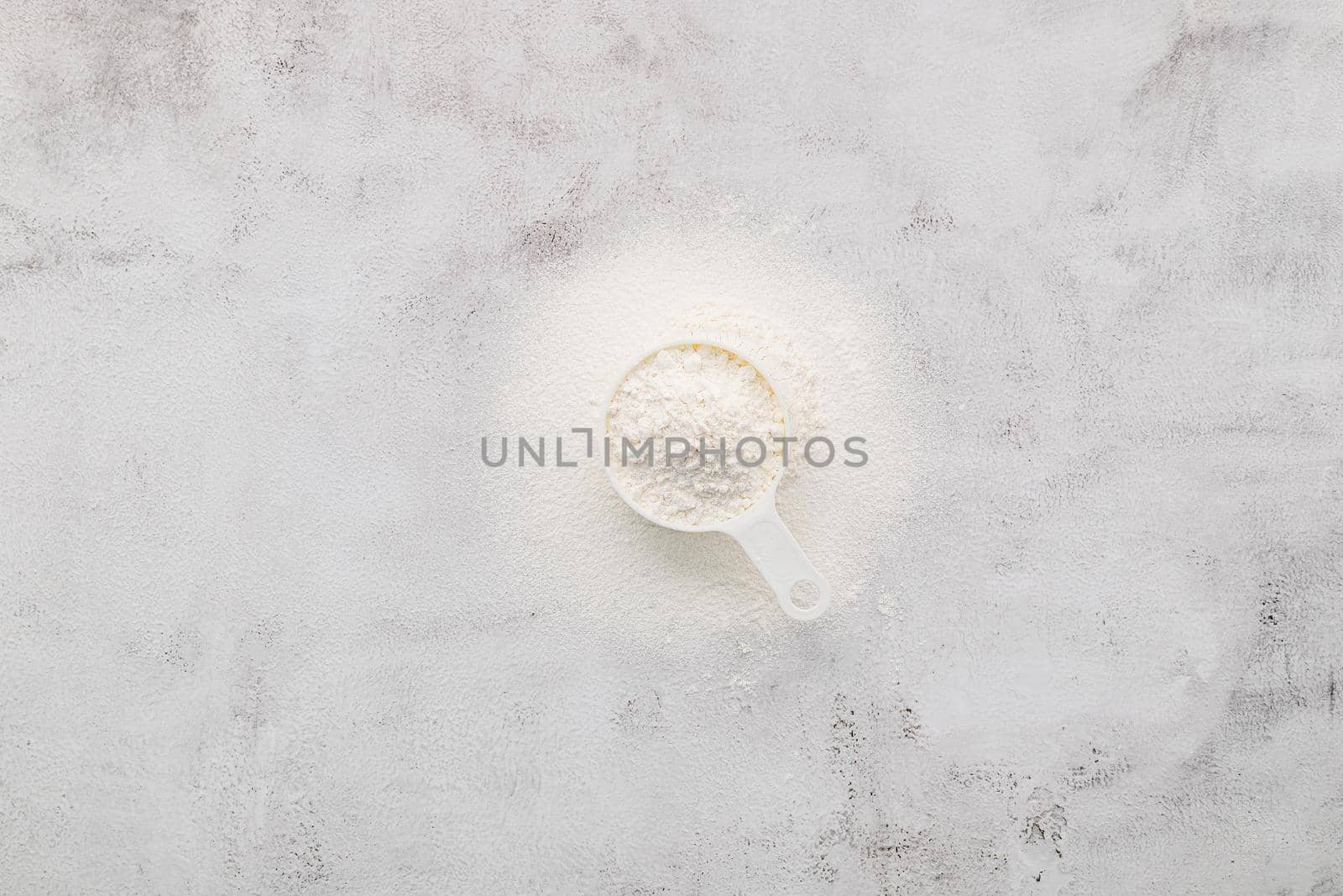 The ingredients for homemade pizza dough measuring cup wheat flour set up on white concrete background.