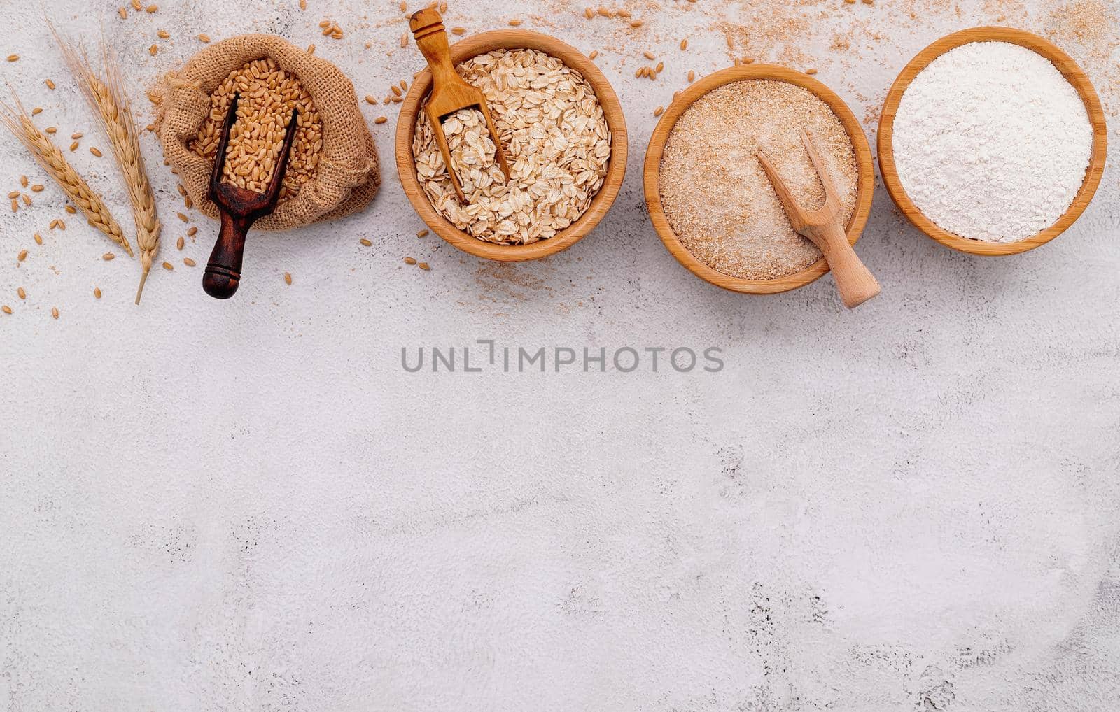  Wheat grains , brown wheat flour and white wheat flour in wooden bowl set up on white concrete background. by kerdkanno