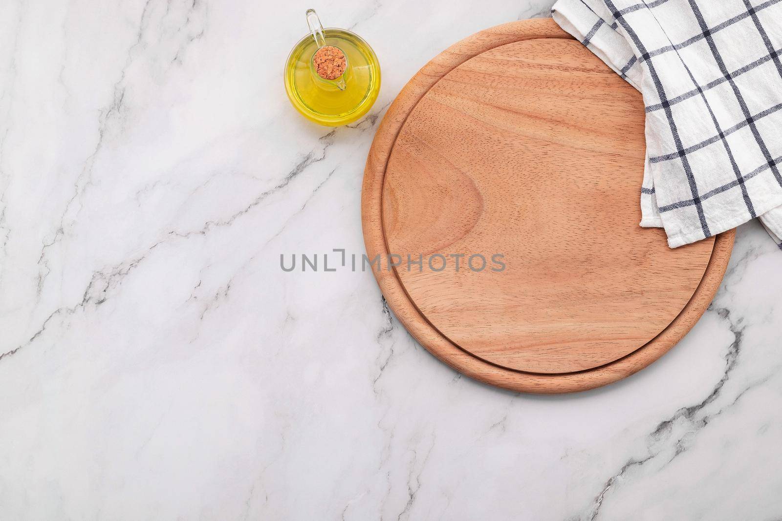 Empty wooden pizza platter with napkin  set up on marble stone kitchen table. Pizza board and tablecloth on white marble background.