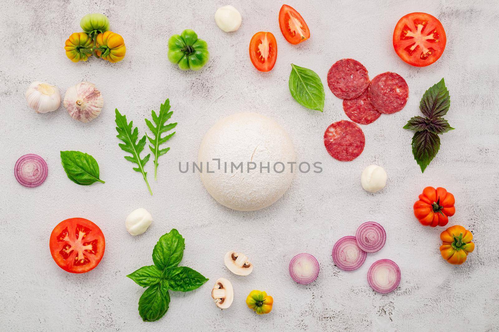 The ingredients for homemade pizza set up on white concrete background.