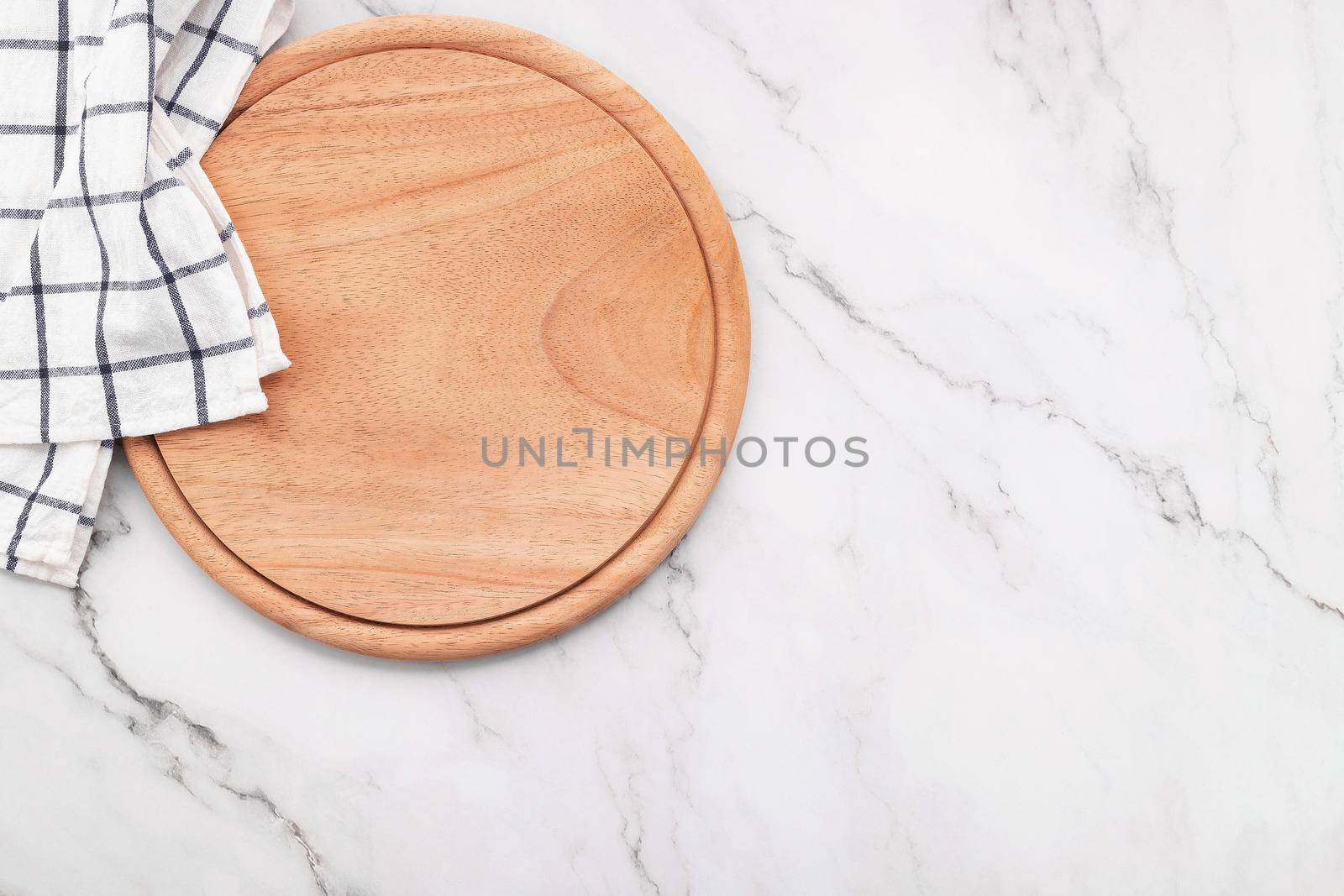 Empty wooden pizza platter with napkin and rolling pin set up on marble stone kitchen table. 