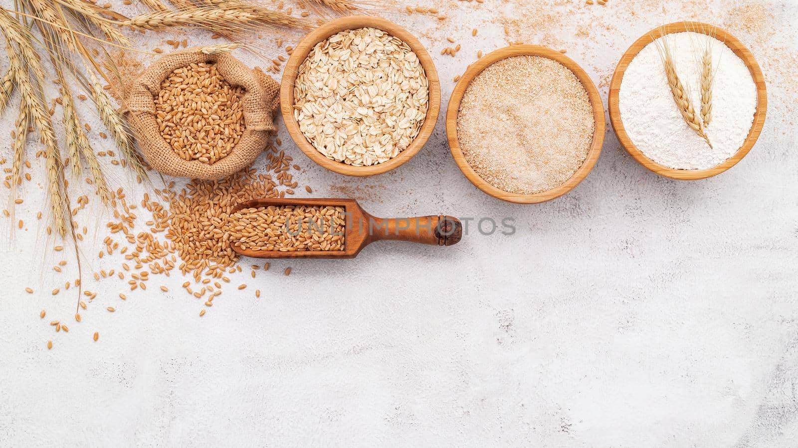  Wheat grains , brown wheat flour and white wheat flour in wooden bowl set up on white concrete background. by kerdkanno