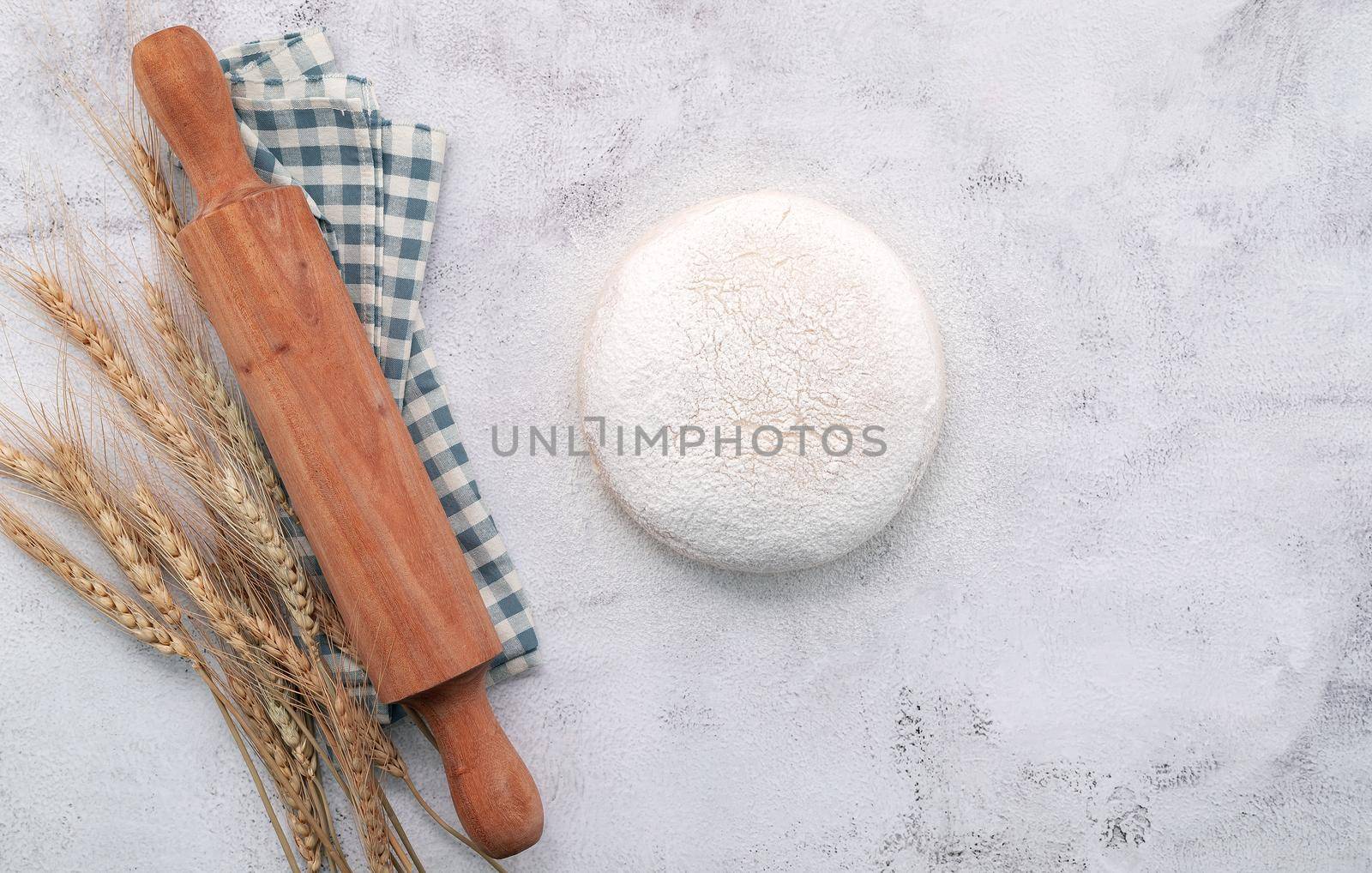 Wheat ears and wheat grains setup with rolling pin on white concrete background.