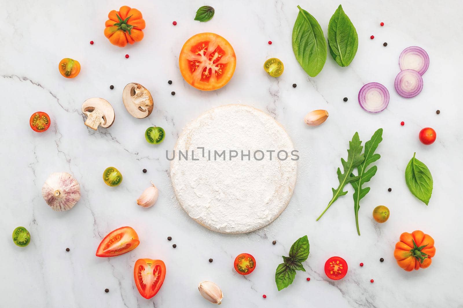 The ingredients for homemade pizza set up on white marble background.