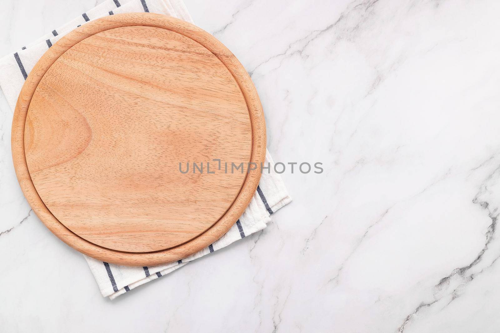 Empty wooden pizza platter with napkin  set up on marble stone kitchen table. Pizza board and tablecloth on white marble background. by kerdkanno