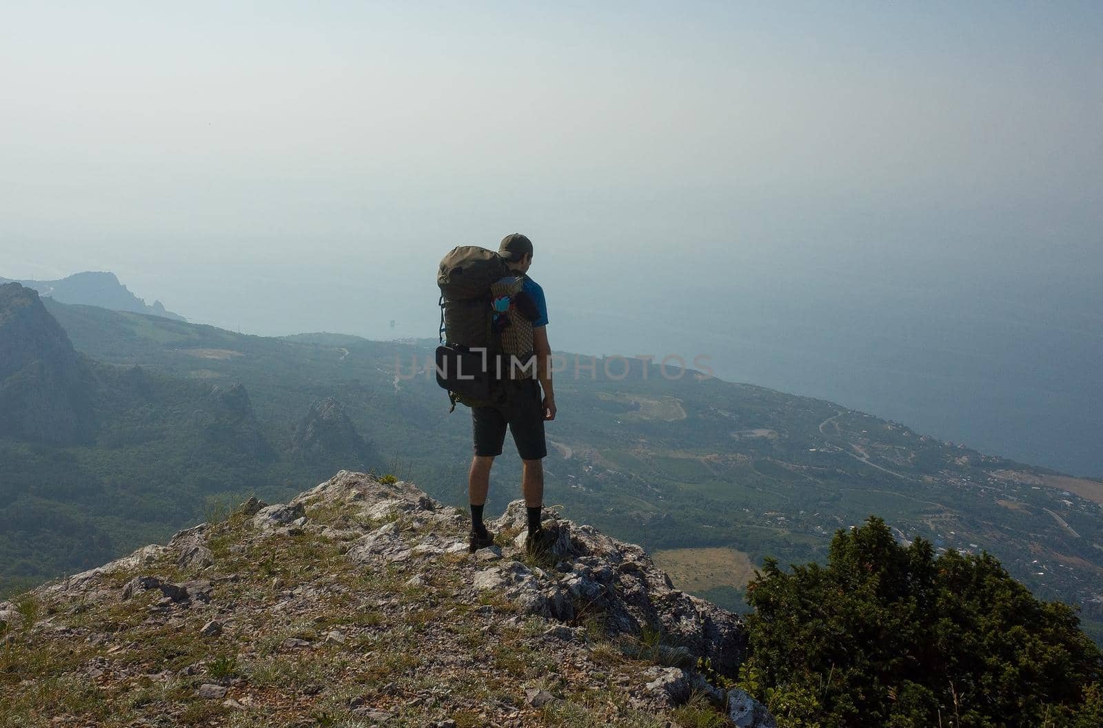 A tourist with a large backpack admires the landscape, standing on the edge of the abyss.