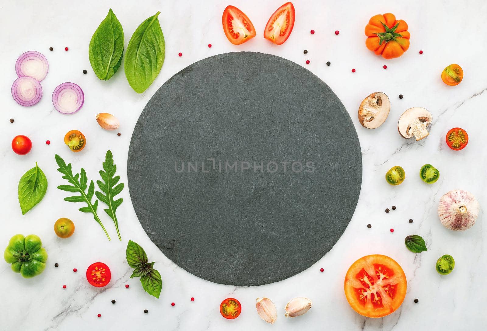 The ingredients for homemade pizza set up on white marble background.