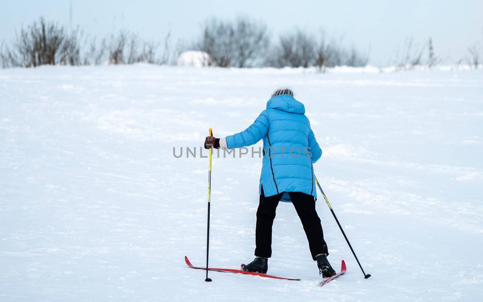 A woman in a blue jacket skiing up a snowy slope.