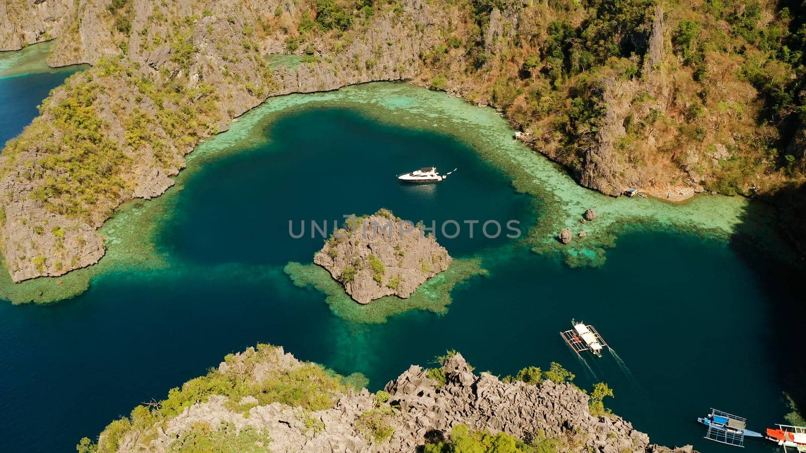 Aerial view tourist boats in lagoon. Kayangan Lake. lagoons, mountains covered with forests.coves with blue water among the rocks. Seascape, tropical landscape. Palawan, Philippines