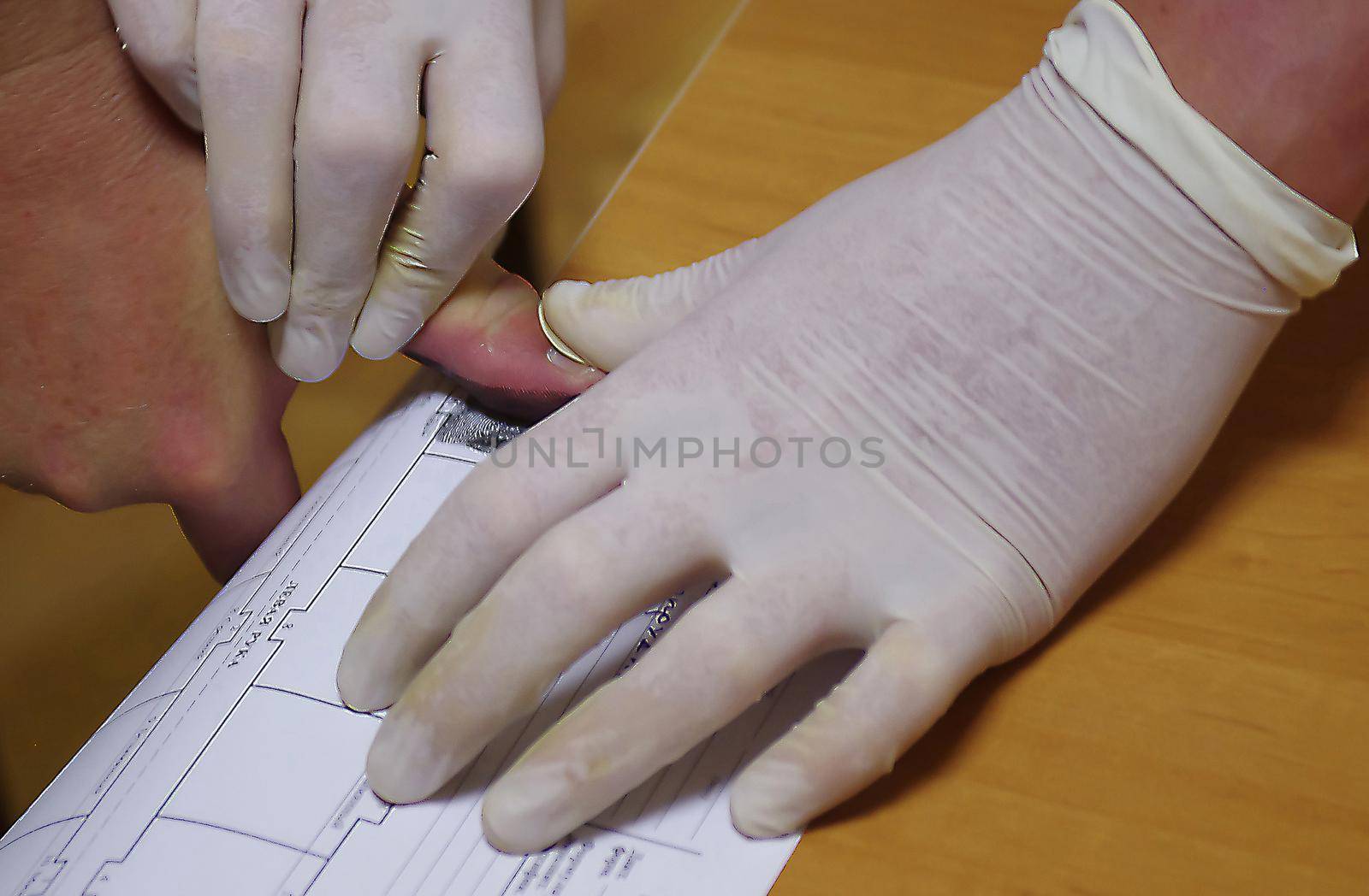 A police officer wearing rubber gloves takes a fingerprint of a suspect.