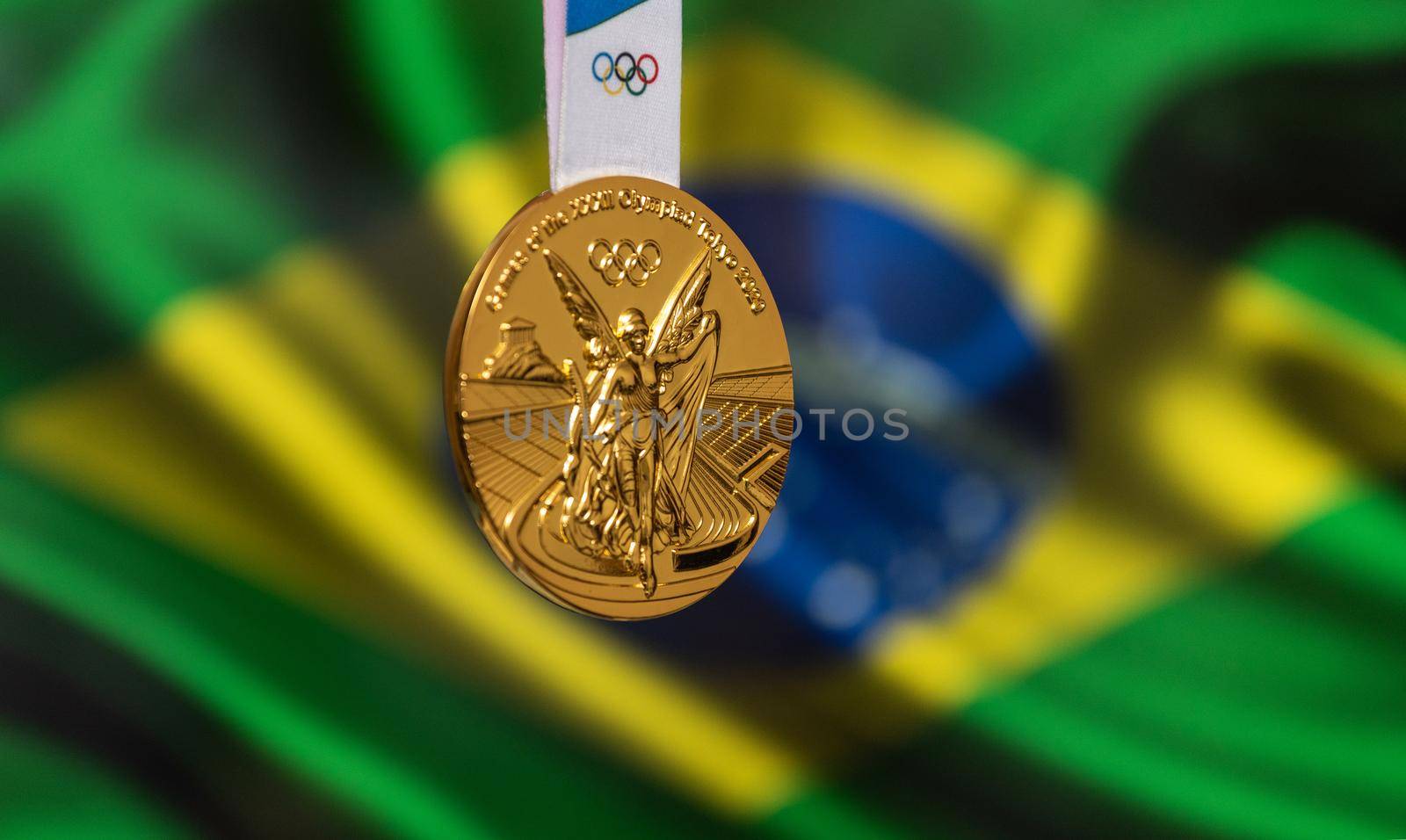 April 25, 2021 Tokyo, Japan. Gold medal of the XXXII Summer Olympic Games 2020 in Tokyo on the background of the flag of Brazil.