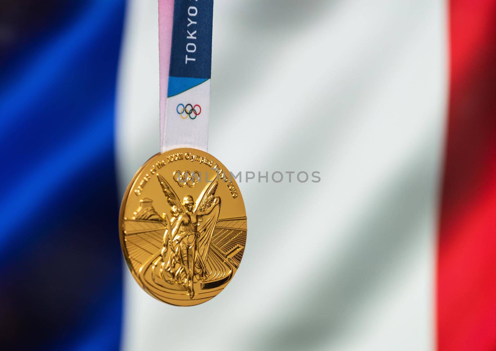 April 25, 2021 Tokyo, Japan. Gold medal of the XXXII Summer Olympic Games 2020 in Tokyo on the background of the flag of France.