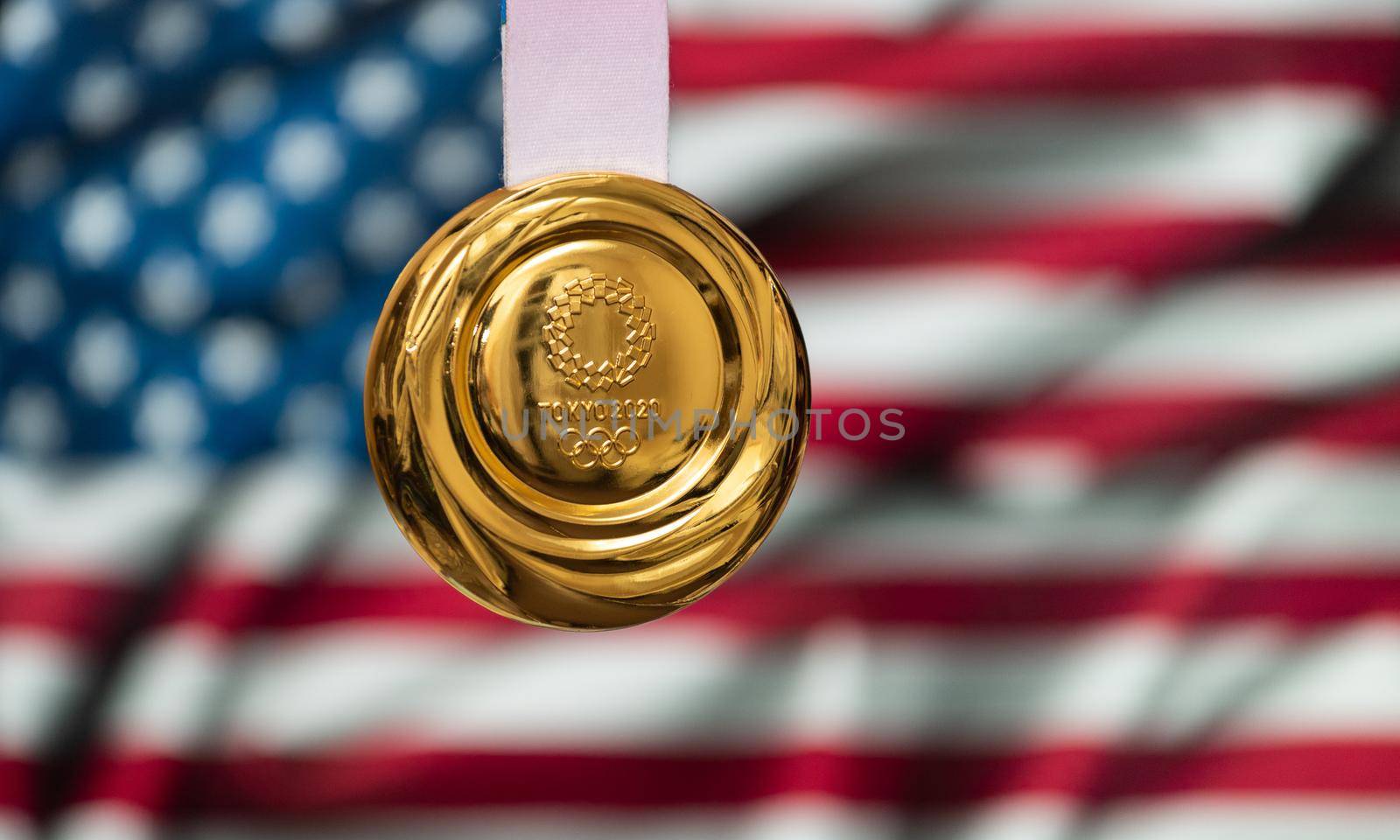 April 25, 2021 Tokyo, Japan. Gold medal of the XXXII Summer Olympic Games 2020 in Tokyo on the background of the US flag.