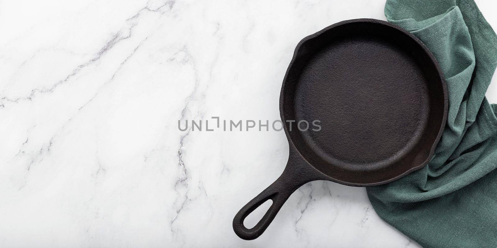 Empty old cast iron skillet set up on white marble  background with flat lay and copy space. by kerdkanno