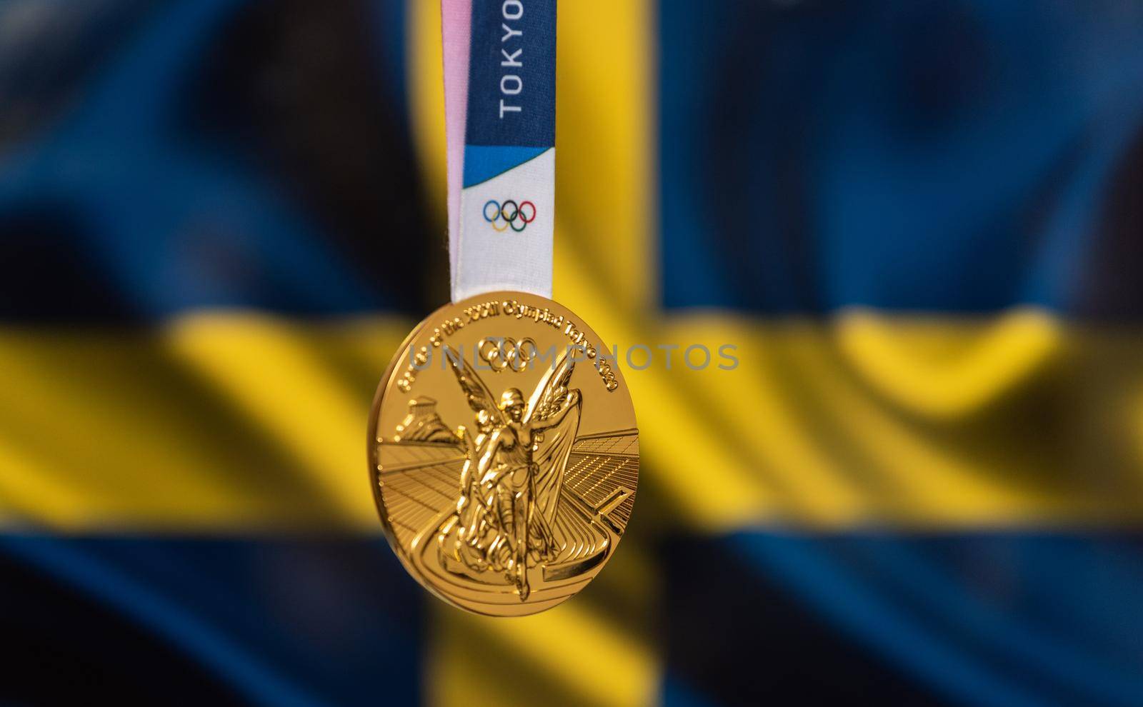 April 25, 2021 Tokyo, Japan. Gold medal of the XXXII Summer Olympic Games 2020 in Tokyo on the background of the flag of Sweden.