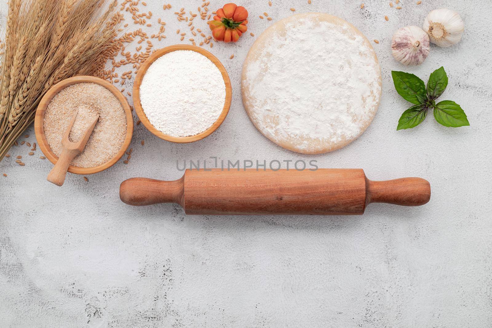 The ingredients for homemade pizza dough with wheat ears ,wheat flour and wheat grains set up on white concrete background.