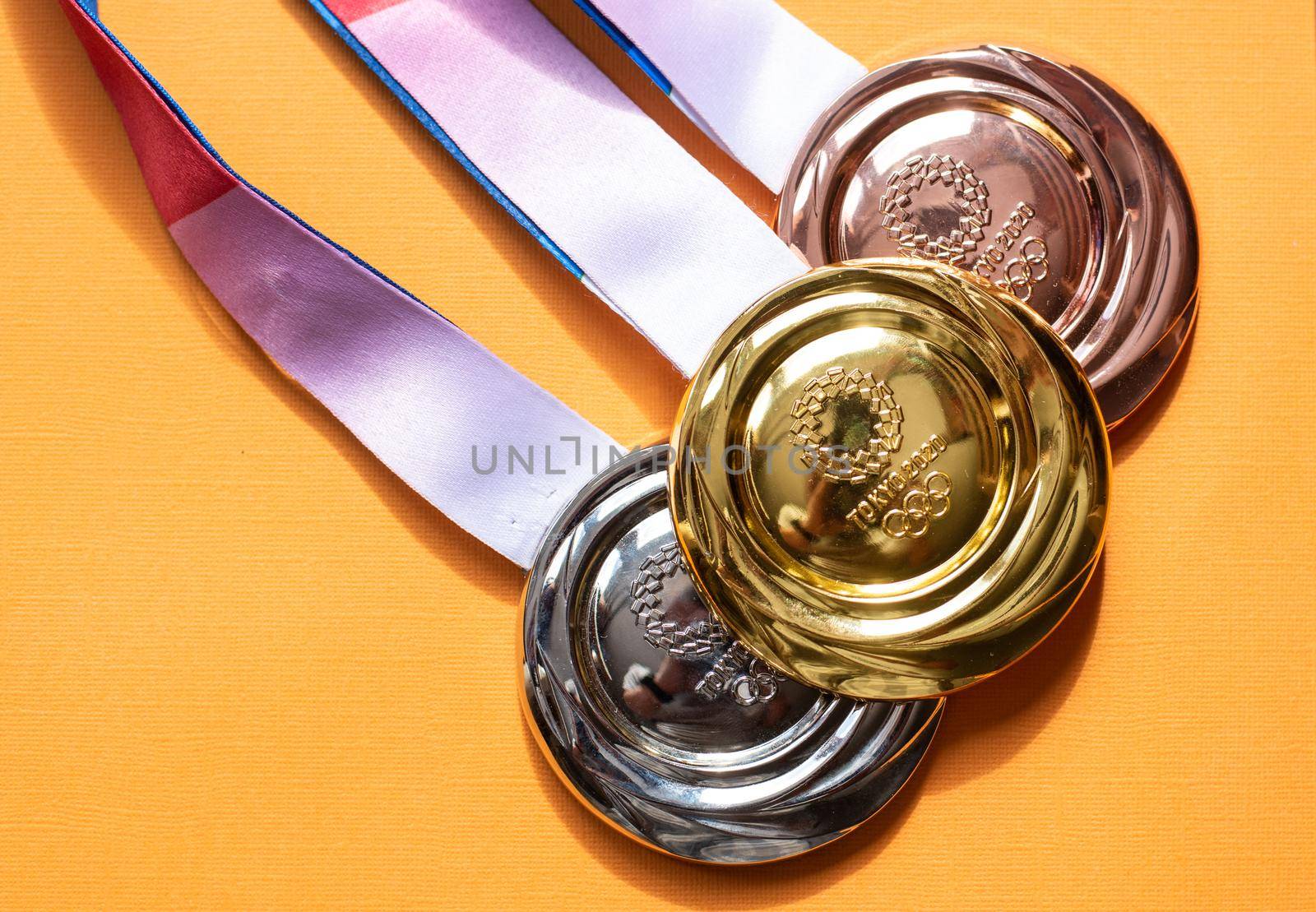 April 25, 2021 Tokyo, Japan. Gold, silver and bronze medals of the XXXII Summer Olympic Games in Tokyo on a yellow background.