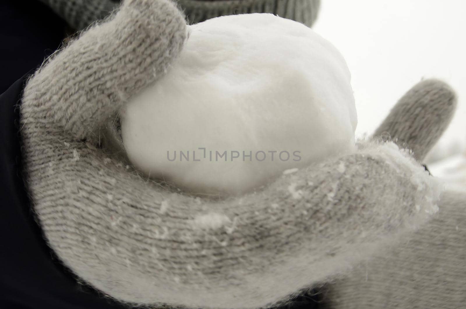 A snowball made from freshly plowed snow, in a hand in a gray woolen glove. by fifg