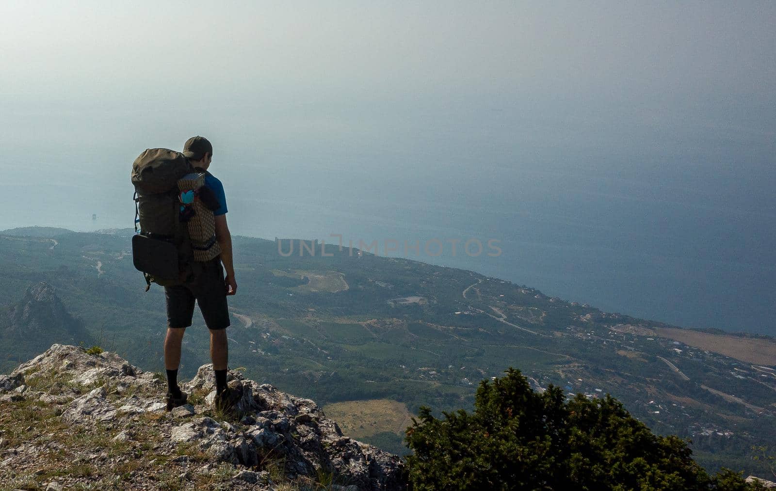 A tourist with a large backpack admires the landscape, standing on the edge of the abyss.